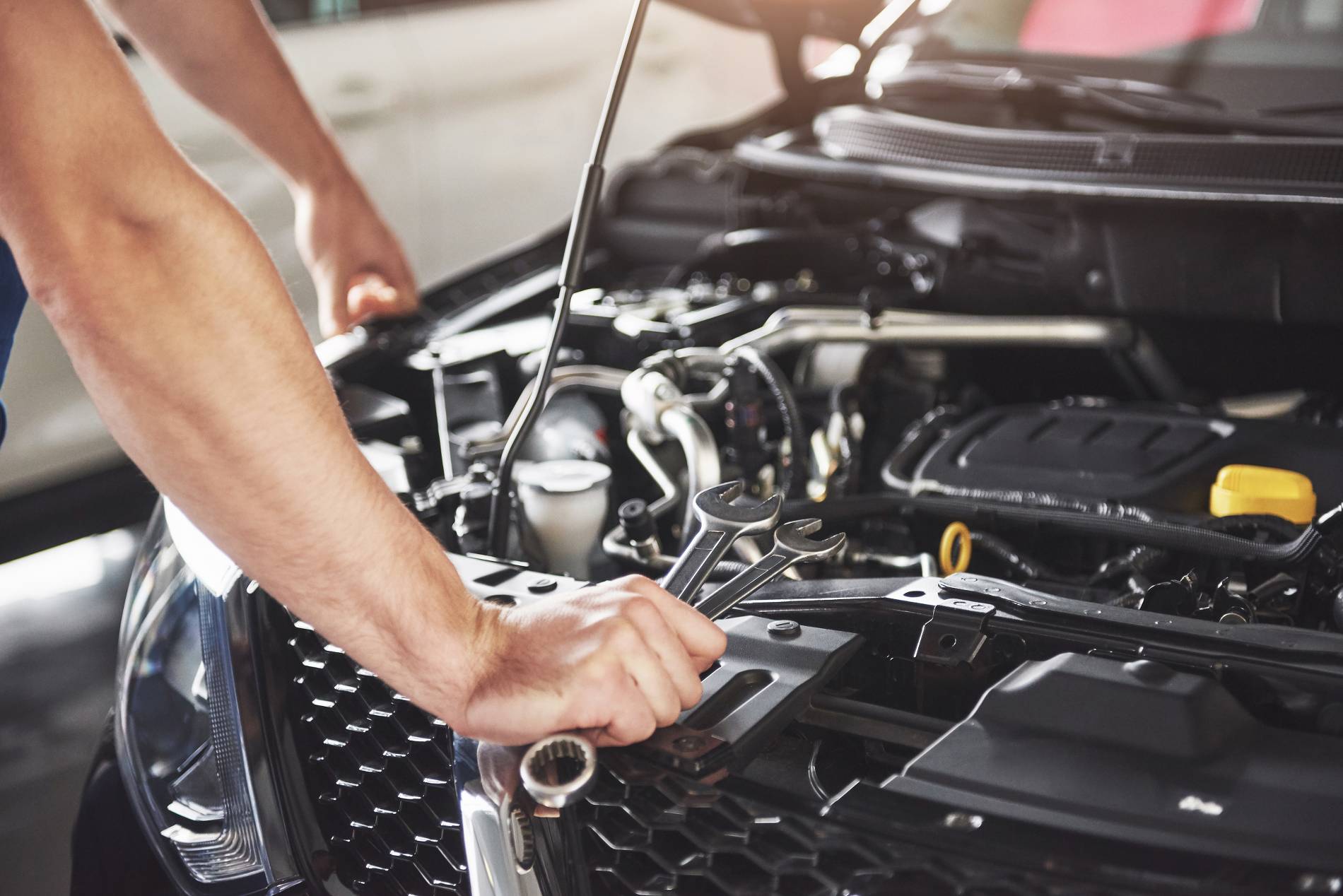 Intervention mécanique sous le capot d’une voiture lors de l’entretien du moteur